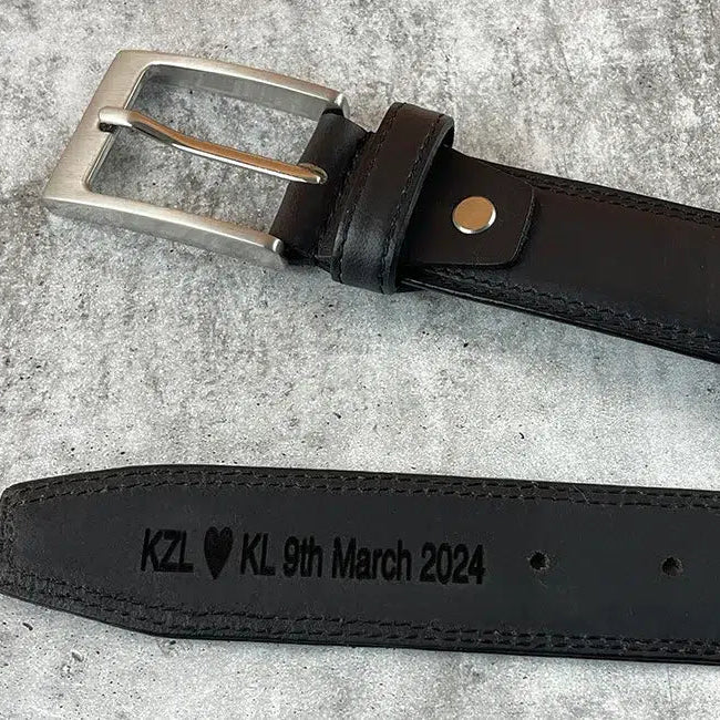 Personalised black leather men’s belt with silver buckle and engraved message “KZL ♥ KL 9th March 2024” on the inside strap.