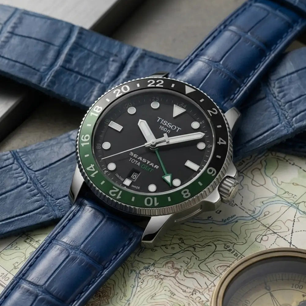 Tissot Seastar GMT watch fitted with a blue crocodile leather watch strap, styled on a vintage map beside a brass compass to emphasize premium craftsmanship and adventure-ready sophistication.