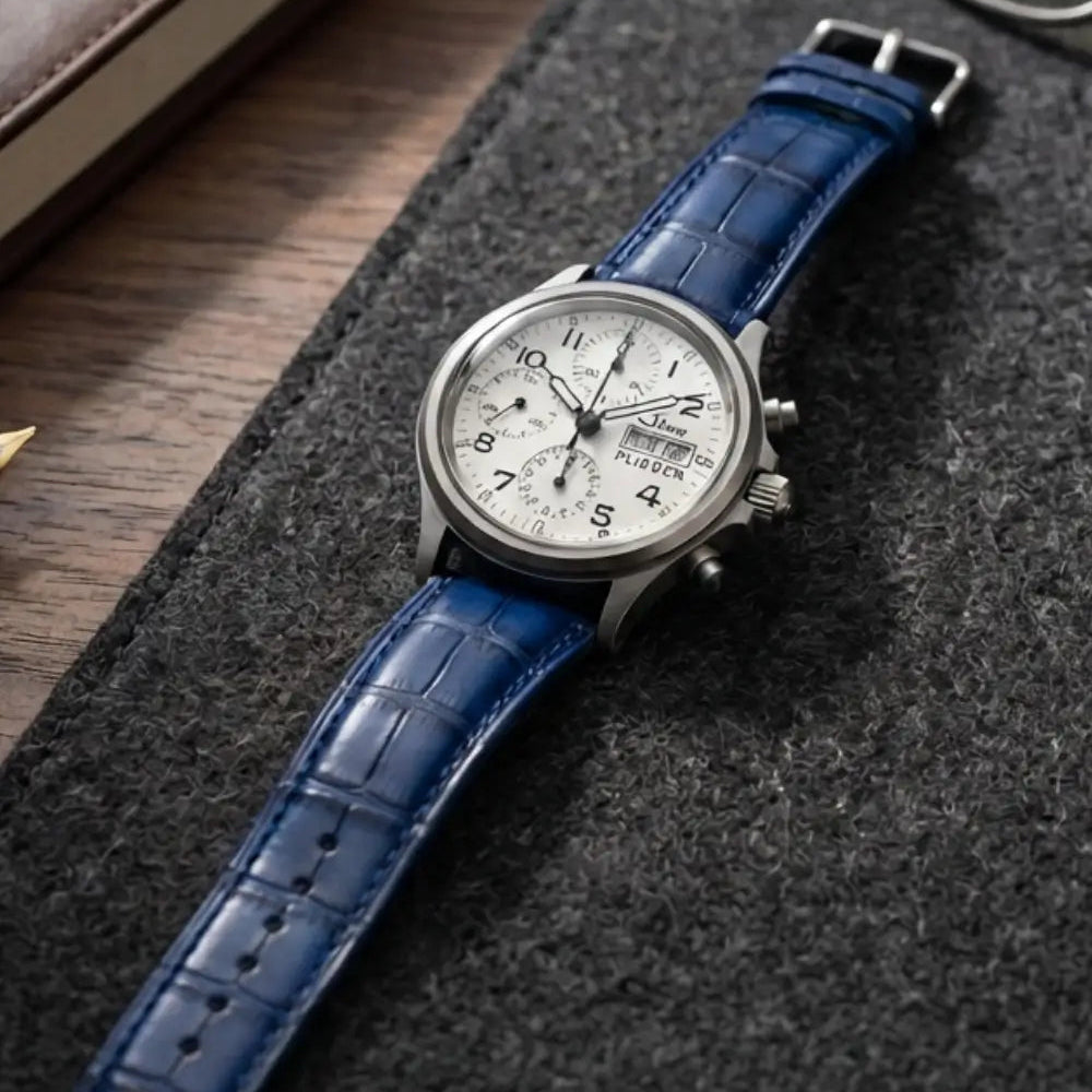 Luxury chronograph watch paired with a blue crocodile leather watch strap displayed on a desk beside a leather notebook and glasses, highlighting refined style and handcrafted leather details.