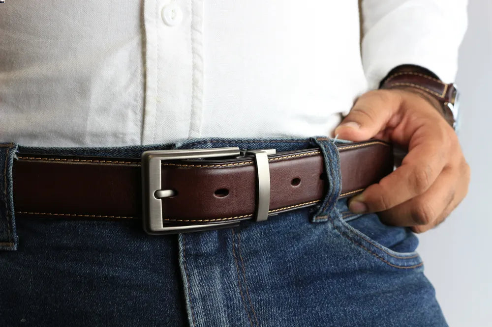 a person wearing a leather belt with blue jeans and white shirt