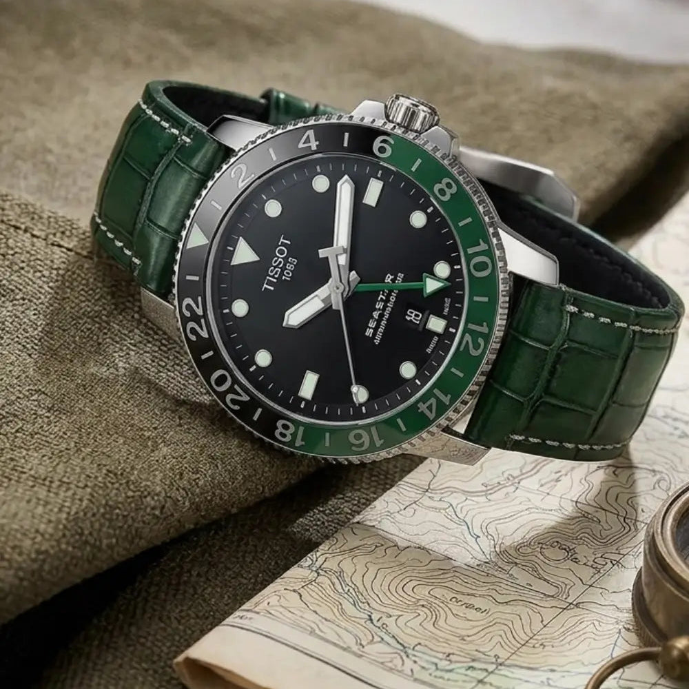 Tissot Seastar GMT watch with a handcrafted green crocodile leather watch strap displayed on a vintage topographic map beside a brass compass, highlighting luxury craftsmanship and travel-ready elegance.