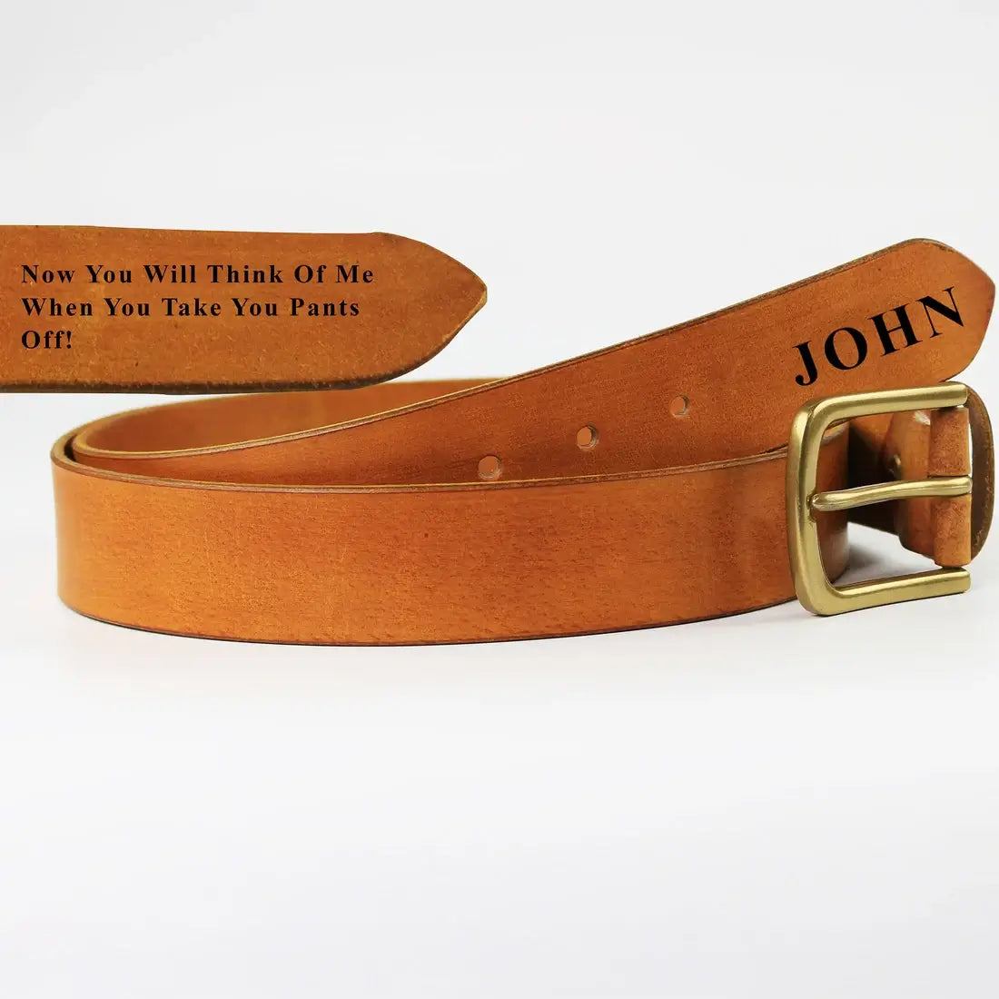 Close-up of personalised cognac leather men’s belt showing engraved message and name near the belt end with brass buckle.