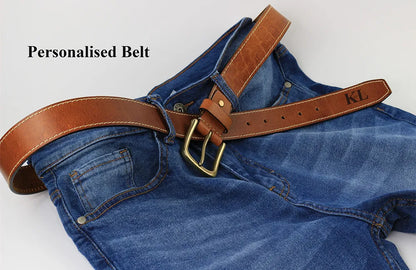Brown leather men’s belt with antique brass buckle styled through blue jeans for a casual everyday menswear look.