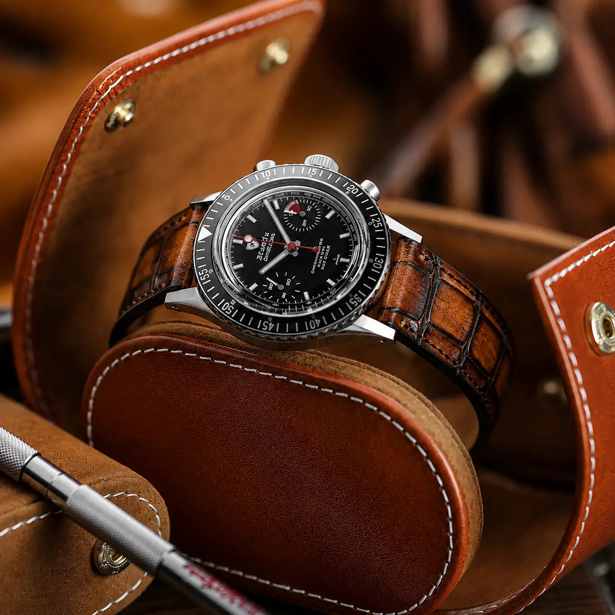 Luxury cognac brown crocodile leather watch strap with a high-definition embossed grain, fitted to a Nivada Grenchen Chronomaster inside a premium leather watch roll.
