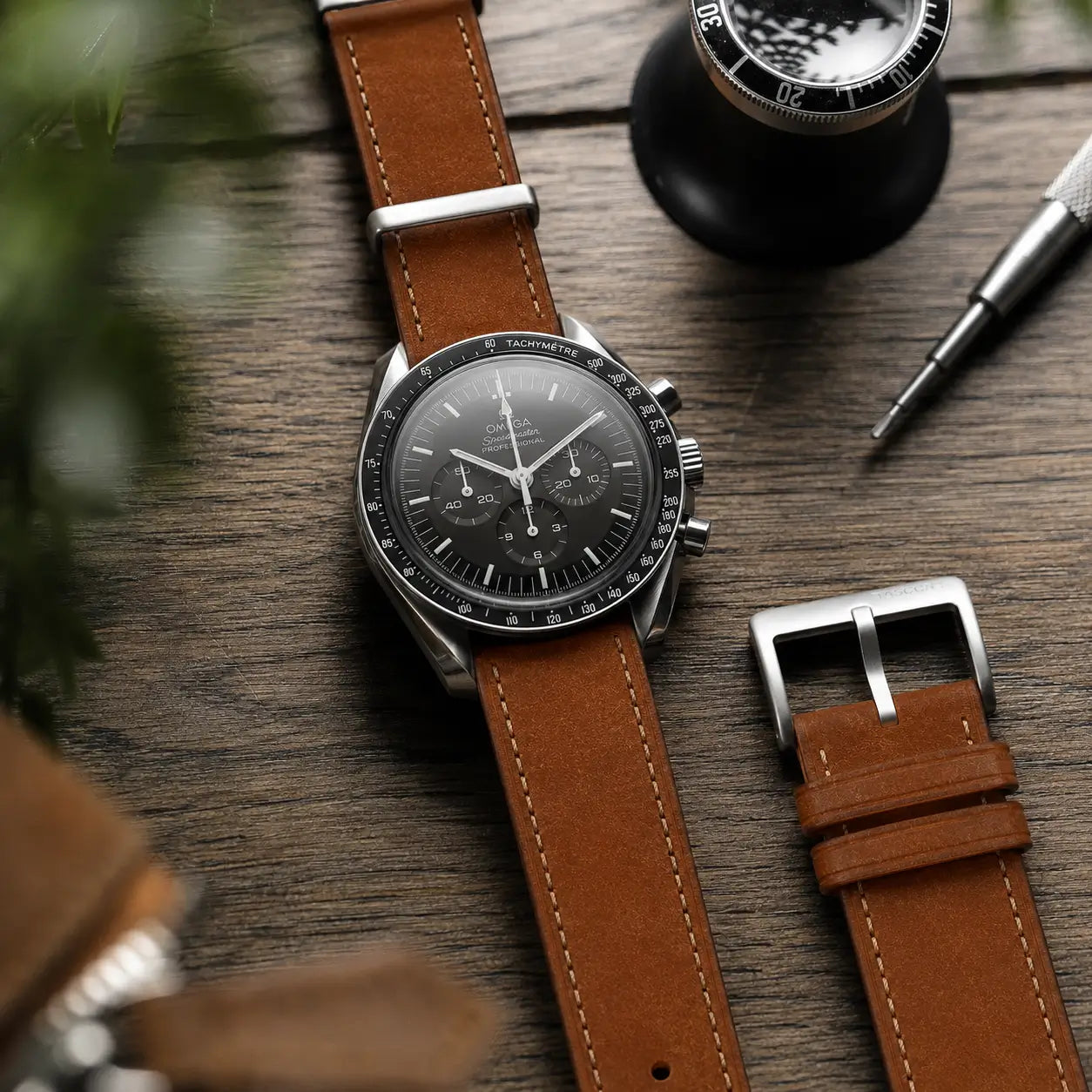 20mm Brown Italian Pueblo leather watch strap with contrast stitching fitted on Omega Speedmaster, premium handmade watch band with stainless steel buckle on wooden desk.