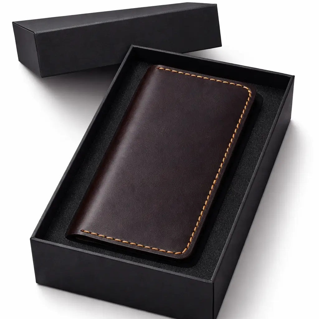 Dark brown leather wallet with contrast stitching presented inside an open black gift box with a foam insert, shown on a clean white background as a premium gift item.