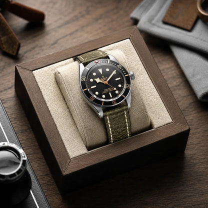 22mm Olive green leather watch strap on Tudor Black Bay watch displayed in a premium watch box, featuring textured leather and contrast stitching.