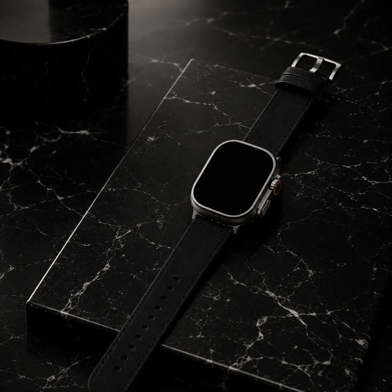 Apple Watch Ultra wearing a black leather strap presented atop polished Nero Marquina marble with subtle reflections and deep shadow layering. Museum-style spotlighting creates a sophisticated monochrome luxury atmosphere while showcasing the craftsmanship and keeping the screen completely black.