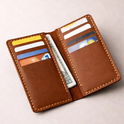 Open brown leather wallet with multiple card slots filled with cards and cash in the center compartment, showcasing organized storage and detailed stitching on a clean neutral background.
