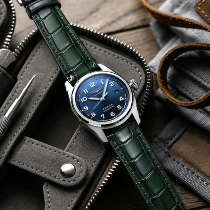 Emerald green crocodile leather watch strap with a high-gloss finish, shown on a blue dial Longines Spirit Chronometer being held by hand.