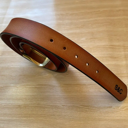 Close-up of brown leather men’s belt showing adjustable holes, edge stitching and personalised initials