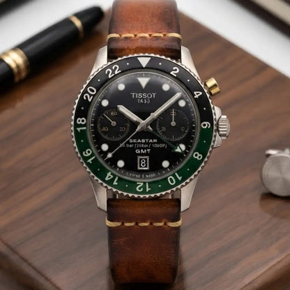 Tissot Seastar GMT watch fitted with a handcrafted vintage brown leather watch strap displayed on a wooden desk beside a fountain pen and notebooks, showcasing rich leather patina, contrast stitching, and timeless craftsmanship.