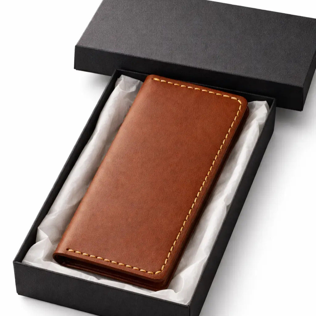 Brown leather wallet with contrast stitching placed inside an open black gift box lined with tissue paper, presented as a premium gifting item on a clean white background.