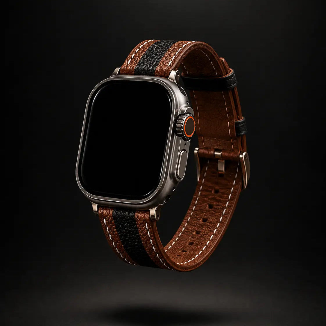 Apple Watch Ultra fitted with the two-tone brown and black leather strap appears suspended against a deep charcoal studio backdrop. A focused overhead spotlight creates sculptural shadows and subtle edge highlights, emphasizing the premium leather texture and brushed metal case. Museum-style luxury presentation with the screen completely off and pure black.