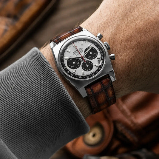Chestnut brown alligator embossed leather watch band with dark brown square scales, worn with a Zenith El Primero Chronomaster on a grey sweater sleeve.