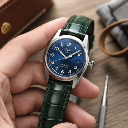 British racing green alligator grain leather watch band with square scales, pictured on a Longines automatic watch inside a grey suede travel pouch.