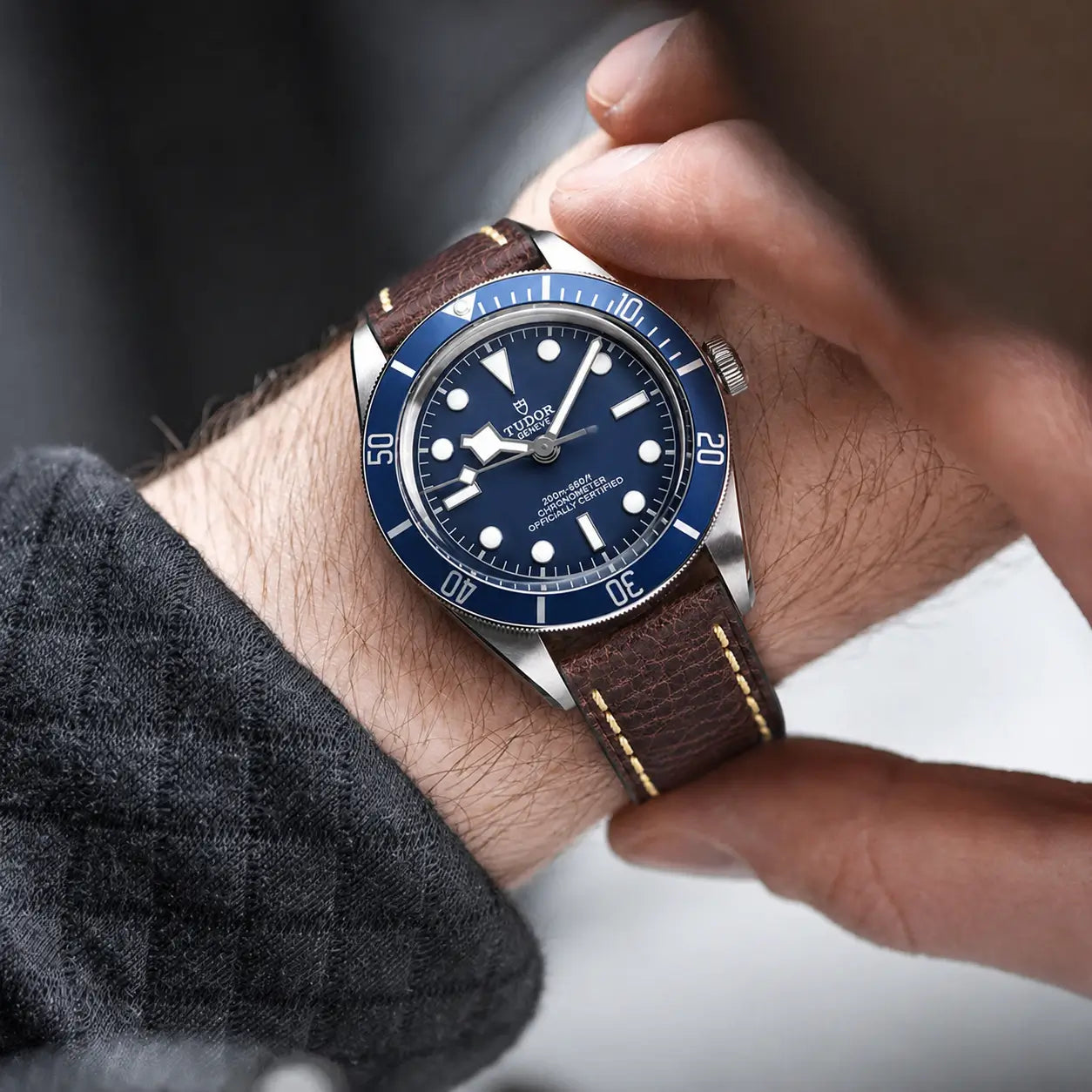 22mm Chestnut brown leather watch strap fitted on Tudor Black Bay watch on wrist, handcrafted premium watch band with textured grain and vintage styling.